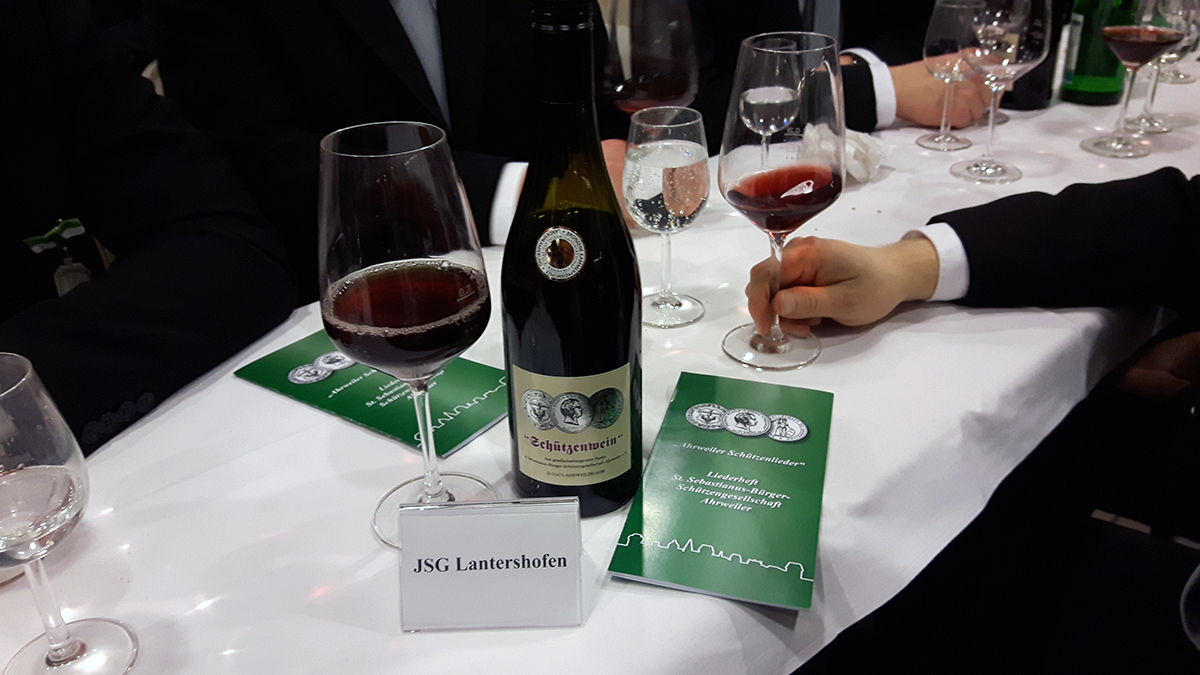 Komposition aus Schützenwein, Schützenliedgut und Schützenplatzschild. Foto: Johannes Schütz