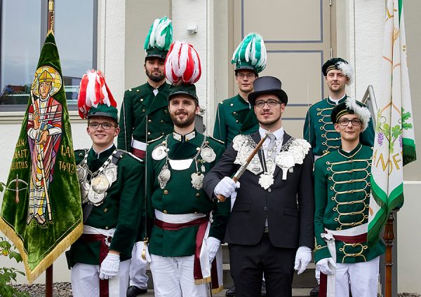 Fahnengruppe 2019 Fahnengruppe an Kirmesmontag 2019: von links nach rechts und von hinten nach vorne: Tragfahnenbegleiter Jonas van den Berghe, Tragfahnenbegleiter Adrian Schmitz, Schwenkfahnenbegleiter Severin Bender / komm. Fähnrich der Tragfahne Felix Wistuba, 1. Offizier Marco Böhm, Majestät Markus Fabritius, komm. Fähnrich der Schwenkfahne Martin Goldbach Anmerkungen: Durch den Königsschuss von Markus Fabritius wurde sein in der Mainacht übernommene Posten des Fähnrichs der Schwenkfahne vakant und Martin Goldbach übernahm diesen an Kirmes 2019 kommissarisch. Durch den Rücktritt von Justin Waldecker wurde sein in der Mainacht übernommene Posten des Fähnrichs der Tragfahne vakant und Felix Wistuba übernahm diesen an Kirmes 2019 kommissarisch. Gewählte Begleiter der Tragfahne: Jonas van den Berghe, Severin Bender; Gewählte Begleiter der Schwenkfahne: Christian Herz, Felix Wistuba Foto: Sven Krämer